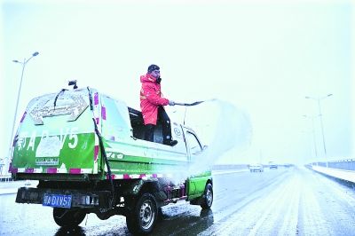  昨日8時(shí)30分，洪山城管局機(jī)掃隊(duì)的隊(duì)員在野芷湖大橋撒鹽化雪 記者周超 攝(信息來源：雷霓雰) 